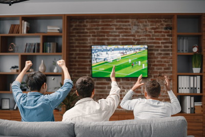 men sat on sofa at home watching football